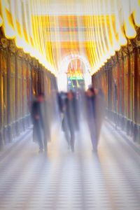 Blurred motion of people walking in illuminated corridor