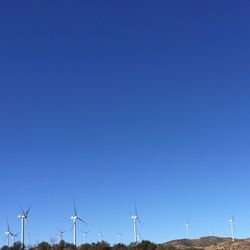 Low angle view of windmill against clear blue sky