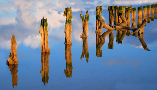 Panoramic view of wooden posts in lake against sky