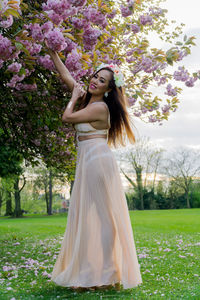 Portrait of beautiful young woman posing by cherry blossoms at park