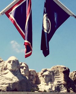 Low angle view of flags hanging against clear blue sky