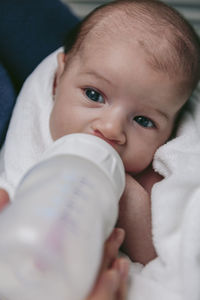 Midsection of mother feeding son with milk bottle