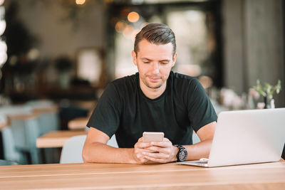 Man using mobile phone while sitting on table