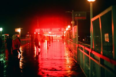 Wet illuminated street against sky at night