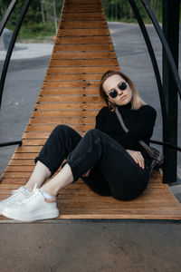 Young beautiful white girl is sitting on a park bench. cute female lifestyle, portrait