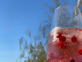 Close-up of glass of water against blue sky
