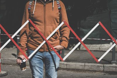 Midsection of mid adult man holding disposable cup standing on street