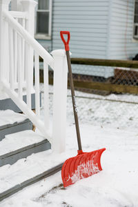 Red snow shovel in snow sitting outside house, shoveling snow outdoors