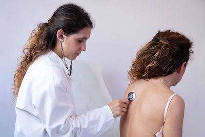 Side view of female doctor examining patient in hospital