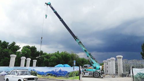 Low angle view of construction site against cloudy sky