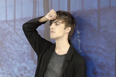 Portrait of young man looking away against wall