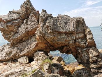 Rock formation in sea against sky