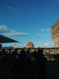 Rear view of people walking in city against sky