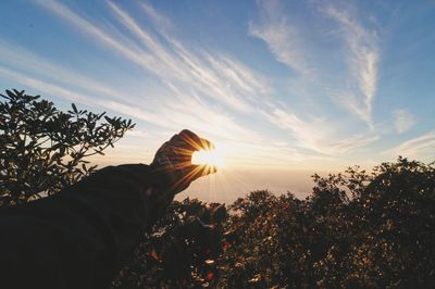 Optical illusion of hand holding sun during sunset