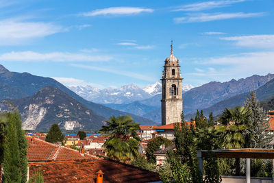 Tower amidst buildings and mountains against sky