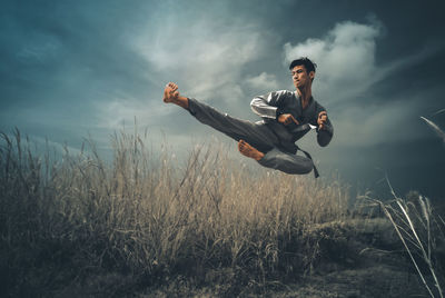 Man jumping over field against sky