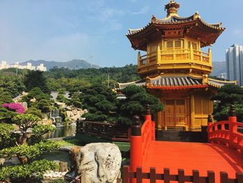 Footbridge leading towards temple against sky