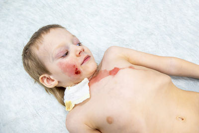 Portrait of shirtless boy lying on floor