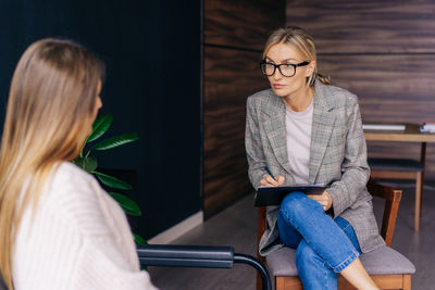 Portrait of a female psychotherapist listening attentively to a woman client at a session