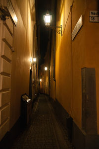 Empty illuminated alley amidst buildings in city at night