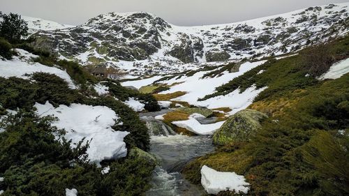 Scenic view of stream and mountains against sky