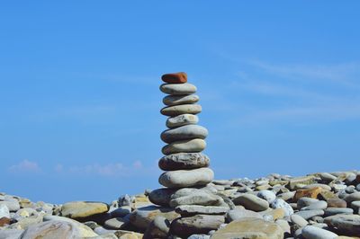 Stack of pebbles on beach against blue sky