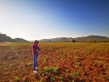 Rear view of woman walking on field against clear sky