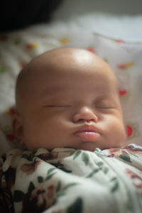 Close-up of cute baby boy sleeping on bed at home