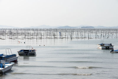 Boats sailing on sea against clear sky