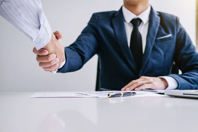 Midsection of businessman shaking hands with colleague