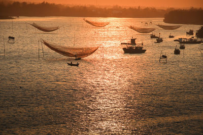 Scenic view of lift nets at sea against sky during sunset