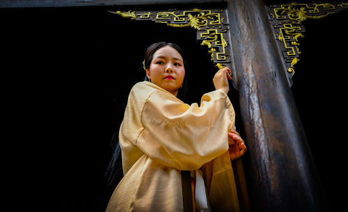 Low angle portrait of woman standing by door