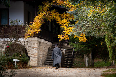 Rear view of man walking on street amidst buildings