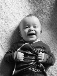 Directly above shot of happy baby boy relaxing on carpet