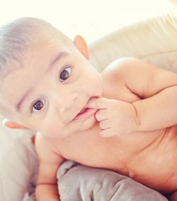 High angle portrait of shirtless baby boy sitting on sofa at home