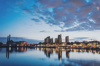 Buildings by river against sky in city