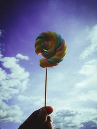 Low angle view of hand holding flower against sky