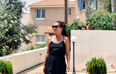 Woman wearing sunglasses while standing by plants