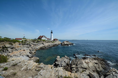 Lighthouse by sea against sky