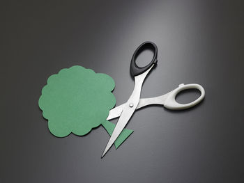 Close-up of scissor and paper tree on gray background