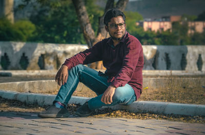 Young man looking away while sitting outdoors