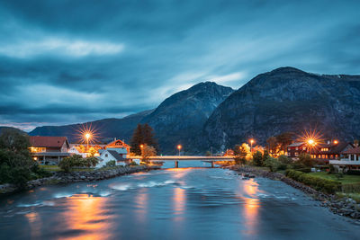 Illuminated bridge over river against sky at night