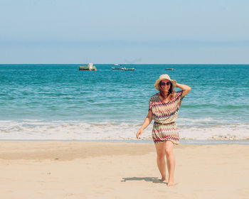 Rear view of woman standing at beach against clear sky