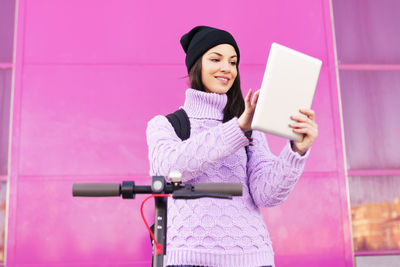 Full length of a smiling young woman using smart phone