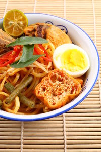 Close-up of noodles soup in bowl on place mat