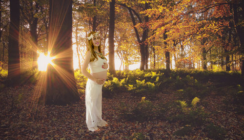 Woman standing on field against trees during autumn