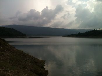 Scenic view of lake and mountains against cloudy sky