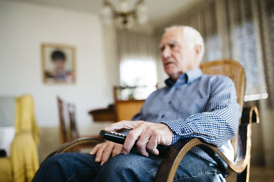 Hand of senior man holding remote control, close-up