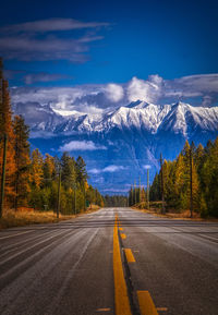 Road amidst trees and mountains against sky