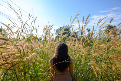 Rear view of woman standing on field against sky